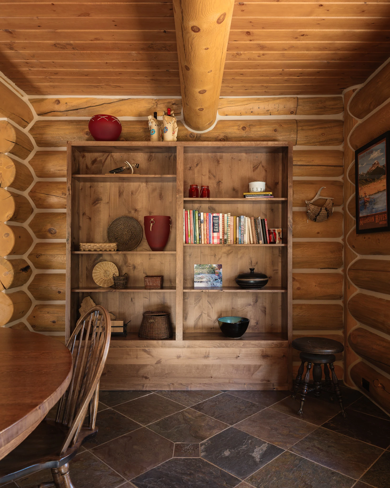 Built-in log wall bookshelf styled with pottery and books — interior design photography Livingston Montana, Sam Schlauch Designs